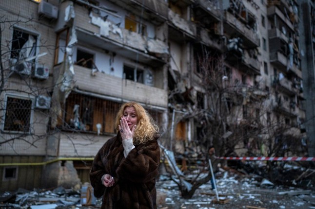 Natali Sevriukova cries in front of the building that was her home following a rocket attack in Kyiv, Ukraine, on Feb. 25, 2022. (AP Photo/Emilio Morenatti)