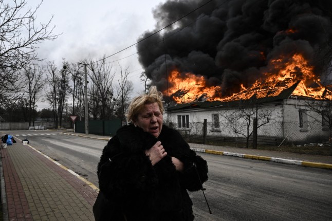 (FILES) A woman reacts as she stands in front of a house burning after being shelled in the city of Irpin, outside Kyiv, on March 4, 2022. More than 1.2 million people have fled Ukraine into neighbouring countries since Russia launched its full-scale invasion on February 24, United Nations figures showed on March 4, 2022. (Photo by Aris Messinis / AFP) (Photo by ARIS MESSINIS/AFP via Getty Images)