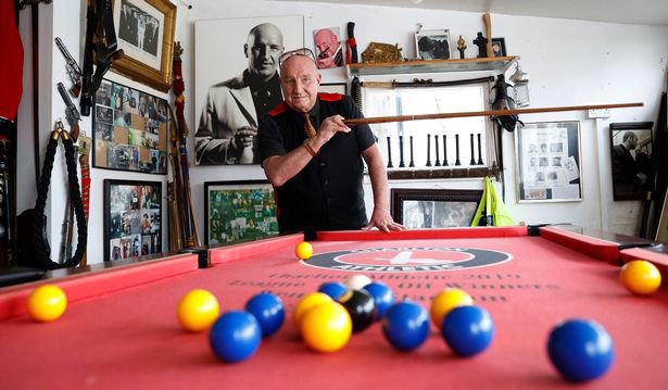 Dave plays pool, surrounded by pictures of his friends and family - In one unassuming corner of South East London, you can find an incredible 'castle' that sticks out like a sore thumb. The brilliant white mansion - owned by a self-proclaimed ex-gangster - is decked out with guns, swords, and suits of armour (all fake, of course), pictures of the late Queen, and even a bust of his own head. Camelot Castle is home to Dave Courtney, a reformed gang member who claims to have links to the Kray twins and be the inspiration for Vinnie Jones' character in Lock, Stock, and Two Smoking Barrels, and who Plumstead locals may know as the owner of the peacock that escaped and remains on the run.