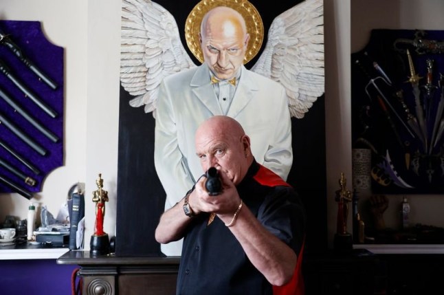 Dave has many prop guns, which he poses with here front of the painting he says has his own blood mixed into the paint - In one unassuming corner of South East London, you can find an incredible 'castle' that sticks out like a sore thumb. The brilliant white mansion - owned by a self-proclaimed ex-gangster - is decked out with guns, swords, and suits of armour (all fake, of course), pictures of the late Queen, and even a bust of his own head. Camelot Castle is home to Dave Courtney, a reformed gang member who claims to have links to the Kray twins and be the inspiration for Vinnie Jones' character in Lock, Stock, and Two Smoking Barrels, and who Plumstead locals may know as the owner of the peacock that escaped and remains on the run.