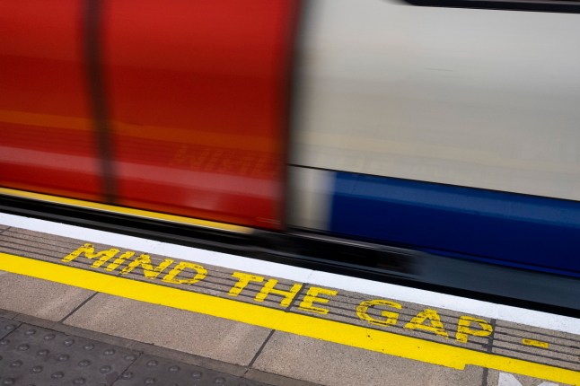 Mind the gap warning text on a London Underground platform, with a Tube train in the background.