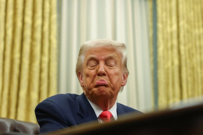 US president Donald Trump pulling a face at a desk.