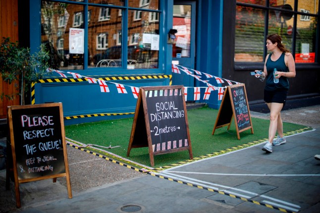 TOPSHOT - A woman walks past a restaurant with social distancing markings in Portobello Market in west London on June 1, 2020, following the easing of the lockdown restrictions during the novel coronavirus pandemic. - Some non-essential stores, car dealerships and outdoor markets in Britain on June 1 were able to reopen from their COVID-19 shutdown in an easing of coronavirus lockdown measures. (Photo by Tolga AKMEN / AFP) (Photo by TOLGA AKMEN/AFP via Getty Images)
