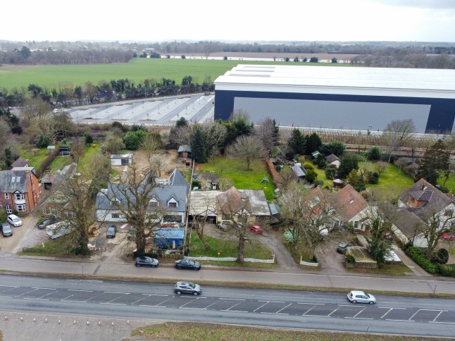 EAST ANGLIA NEWS SERVICE, tel 07767 413379 A view of the wall of the new giant warehouse looming over the back gardens of homes in Nacton near Ipswich, Suffolk. Villagers are outraged by the huge structure
