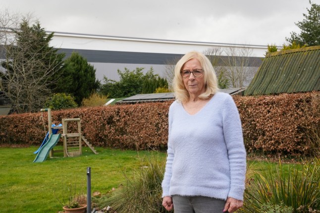 EAST ANGLIA NEWS SERVICE, tel 07767 413379 Jenny Upson who is angry about the new warehouse built at the back of her garden in Nacton, Suffolk, pictured in her garden
