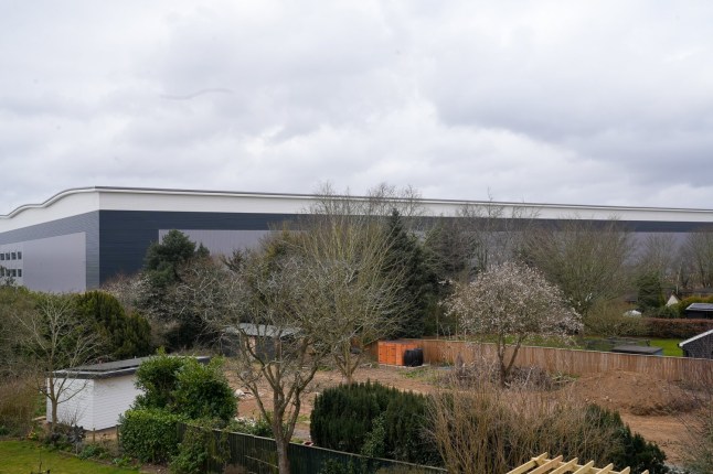 EAST ANGLIA NEWS SERVICE, tel 07767 413379 A view of the wall of the new giant warehouse looming over the back gardens of homes in Nacton near Ipswich, Suffolk. Villagers are outraged by the huge structure