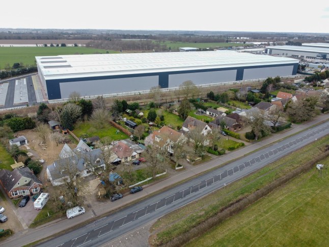 EAST ANGLIA NEWS SERVICE, tel 07767 413379 A view of the wall of the new giant warehouse looming over the back gardens of homes in Nacton near Ipswich, Suffolk. Villagers are outraged by the huge structure
