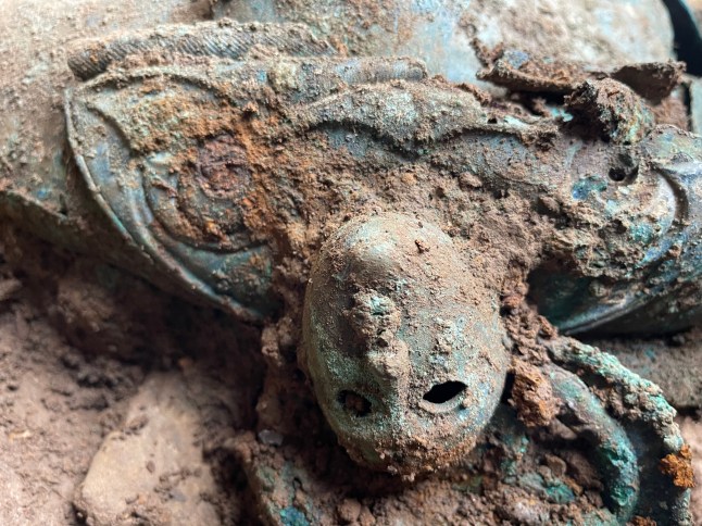 EMBARGOED TO 0001 TUESDAY MARCH 25 Undated handout photo issued by Durham University of a close-up of one of the two mask-like human faces decorating the shoulder of the lidded vessel or cauldron from the Melsonby hoard shown upside down as found during excavation. A huge Iron Age hoard discovered in a Yorkshire field by a metal detectorist could lead to a revaluation of the wealth and status of the elite living in northern Britain 2,000 years ago, an archaeologist has said. Issue date: Tuesday March 25, 2025. PA Photo. See PA story HERITAGE Melsonby. Photo credit should read: Durham University/PA Wire NOTE TO EDITORS: This handout photo may only be used in for editorial reporting purposes for the contemporaneous illustration of events, things or the people in the image or facts mentioned in the caption. Reuse of the picture may require further permission from the copyright holder.
