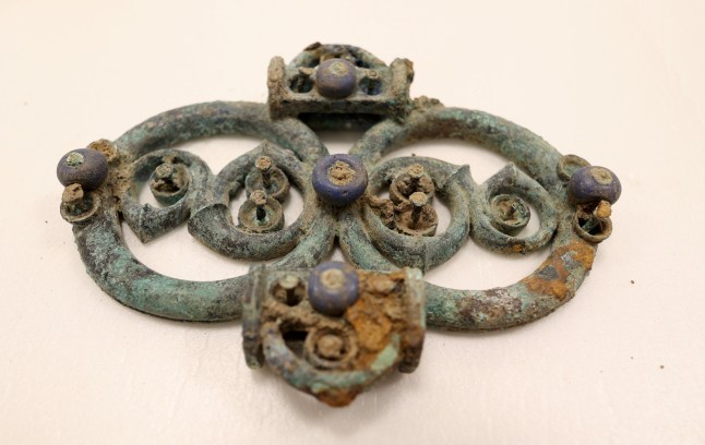 EMBARGOED TO 0001 TUESDAY MARCH 25 Undated handout photo issued by Durham University of a copper alloy strap union (harness fitting) with blue glass decoration from the Melsonby Hoard. A huge Iron Age hoard discovered in a Yorkshire field by a metal detectorist could lead to a revaluation of the wealth and status of the elite living in northern Britain 2,000 years ago, an archaeologist has said. Issue date: Tuesday March 25, 2025. PA Photo. See PA story HERITAGE Melsonby. Photo credit should read: Durham University/PA Wire NOTE TO EDITORS: This handout photo may only be used in for editorial reporting purposes for the contemporaneous illustration of events, things or the people in the image or facts mentioned in the caption. Reuse of the picture may require further permission from the copyright holder.