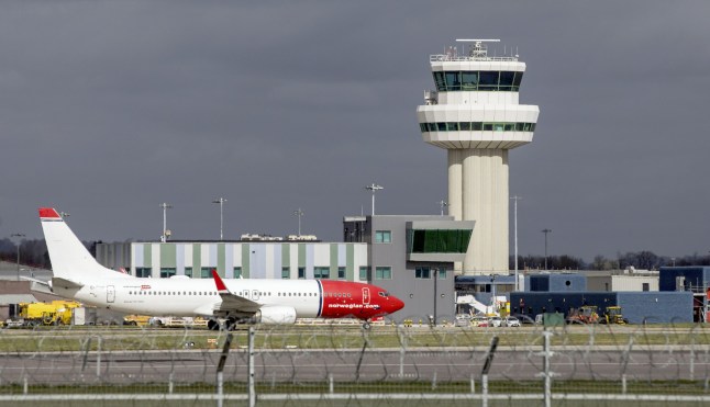 A passenger aircraft, operated by Norwegian Air Shuttle ASA, taxis along the runway in view of the control tower at Gatwick Airport in Crawley
