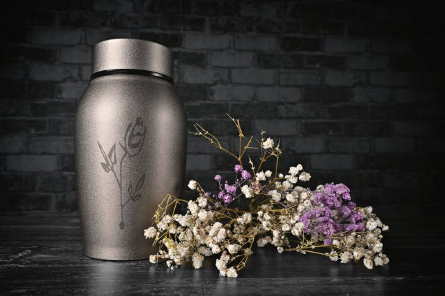 Cremation urn next to a bunch of flowers.