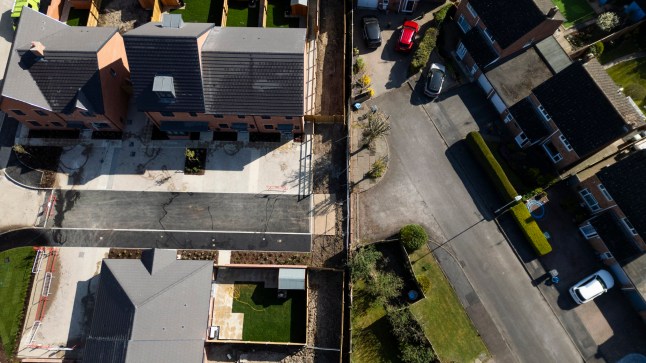 An aerial view show the development and the wall. Release date April 13 2025. A row has broken out between developers of a new build estate and a local over the ownership of a wall - just two bricks high. Lioncourt Homes says it needs to demolish the 'dwarf wall' to create an emergency access route in line with their planning permission. But businessman Roger White says the two-brick high wall next to a development of 70 homes in Hempsted, Gloucester is his. Mr White says the wall is on land he inherited from his father when he passed away in 1997. He says the plot of land was valued at ??10,000 in 2017.