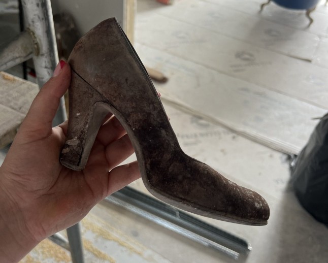 A person holding a woman's high heel.