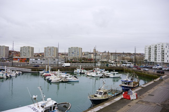 Boulogne. France 03.28.2025 Small fishing vessels moored in the harbor of Boulogne-sur-Mer, with residential buildings and cityscape in the background.