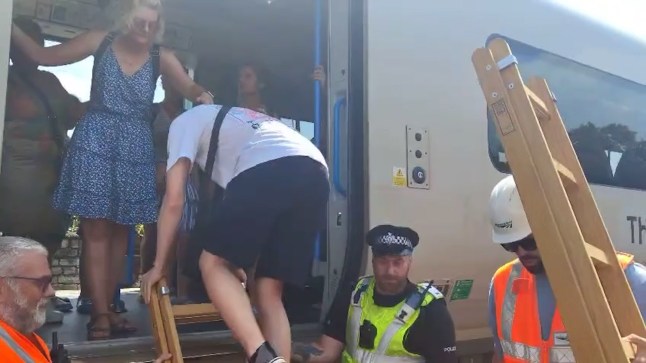 Grabs: Passengers getting evacuated from Brighton train 'after they hit emergency buttons as temperature was getting too hot' Credit: Connor Moore