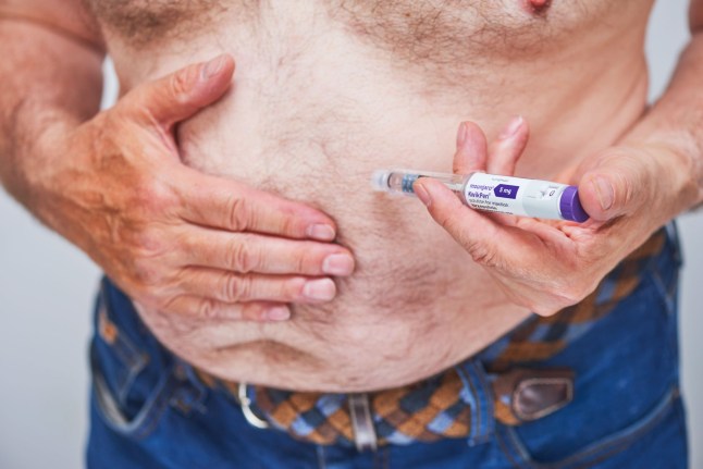A man injecting himself with a Mounjaro weight loss pen.