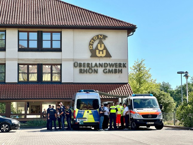 Police and emergency services stand on the premises of power company