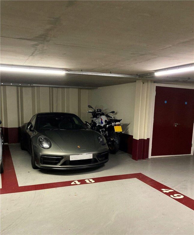 An underground car parking space with a Porsche and a motorbike in it