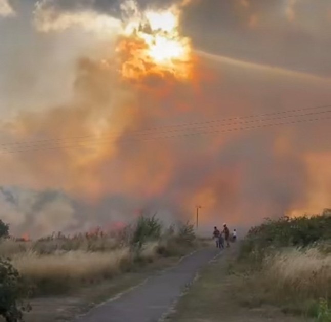 A huge grass fire has broken out behind Clemence Road in Dagenham, with around 125 firefighters and 20 fire engines battling the blaze, which has already scorched eight hectares of grassland, shrubbery, and woodland. The fire, which also involves fences and garden furniture, prompted emergency evacuations of nearby homes. Thick smoke can be seen across parts of Beam Valley Country Park, and residents are urged to keep all doors and windows shut. Firefighters from Multiple Stations Respond The London Fire Brigade???s Control Office began receiving over 75 calls about the fire just after 18:30. Crews from Dagenham, Hornchurch, Wennington, Romford, and other surrounding stations are on scene. A spokesperson confirmed: ???Firefighters are tackling a fire involving around eight hectares of grass, shrubland and trees. Nearby properties are being evacuated as a precaution.??? Public Safety Alert and Road Closures Emergency services have cordoned off roads in the RM10 area, with members of the public advised to avoid the scene entirely. The cause of the fire remains unknown at this stage, and investigations will begin once the fire is under control. Ongoing Coverage The incident comes amid extremely dry conditions during the UK???s heatwave, raising concerns of further wildfires in coming days. This is a developing emergency, and further updates will be provided throughout the evening.