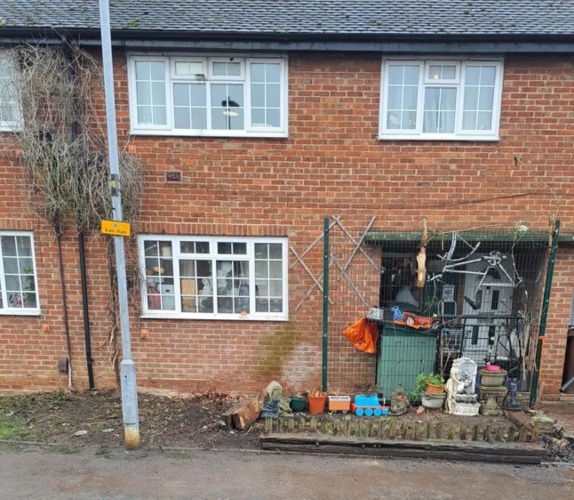 A small brick house with soil at the front