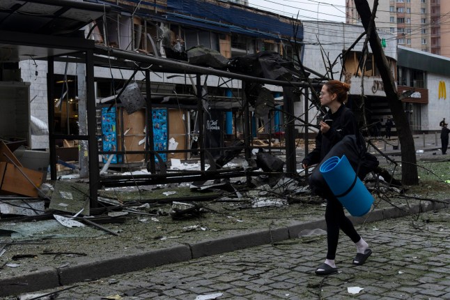 A woman with a carimat walks past wreckage near a metro station following a Russian attack in Kyiv on July 21, 2025, amid the Russian invasion of Ukraine. Russian strikes on Ukraine's capital Kyiv on July 21 killed at least one person and left a shop and school on fire, according to city officials. Four districts of the city were attacked, with reports of burning residential buildings, a kiosk and a kindergarten, Kyiv's mayor Vitali Klitschko said in another Telegram post. (Photo by OLEKSII FILIPPOV / AFP) (Photo by OLEKSII FILIPPOV/AFP via Getty Images)