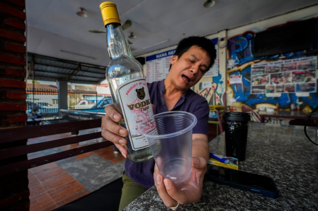 Duong Duc Toan, the manager of Nana Backpack hostel displays a bottle of vodka, in the bar of the hostel in Vang Vieng, Laos, Tuesday, Nov. 19, 2024. (AP Photo/Anupam Nath) 14100599 14104291 14351659 14366833