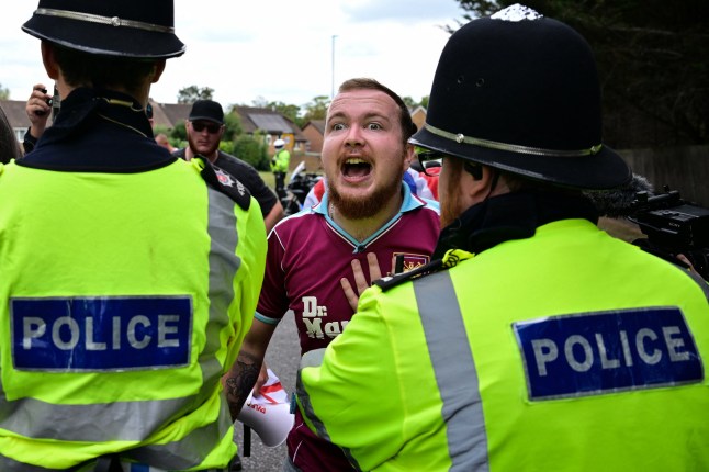 A demonstrator clashes with Police officers during an anti-immigration protest outside the Sheraton Four Points hotel, believed to be housing asylum seekers, in Horley, south of London, on August 23, 2025. A total of 111,084 people applied for asylum in the UK in the year to June 2025 -- the highest number ever. The figures come as Prime Minister Keir Starmer struggles to stem rising support for a hard-right party led by anti-immigrant firebrand Nigel Farage (Photo by Ben STANSALL / AFP) (Photo by BEN STANSALL/AFP via Getty Images)