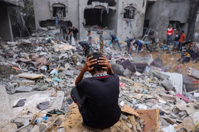 A child reacts as people salvage belongings amid the rubble of a damaged building following strikes on Rafah in the southern Gaza Strip