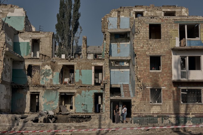 KYIV, UKRAINE - AUGUST 31: People gather to look at the destroyed house during a funeral procession and service for 24-year-old Nadiia and her 2-year-old daughter Angelina on August 31, 2025 in Kyiv, Ukraine. The mother and daughter were killed on August 28th when a Russian missile hit their home in Kyiv. (Photo by Kostiantyn Liberov/Libkos/Getty Images)