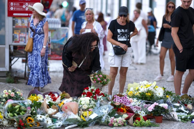 TOPSHOT - CORRECTION / A woman places flowers next to other tributes displayed at the site of the Gloria funicular accident in Lisbon on September 5, 2025. 16 people were killed and 21 injured in a funicular accident on September 3, 2025. The yellow Gloria funicular veered off a steep stretch of tracks evening in one of Lisbon's most popular tourist spots, crashing into a building. (Photo by PATRICIA DE MELO MOREIRA / AFP) / The erroneous mention appearing in the metadata of this photo by PATRICIA DE MELO MOREIRA has been modified in AFP systems in the following manner: [16 people were killed and 21 injured in a funicular accident on September 3, 2025] instead of [16 people were killed and 21 injured in a funicular accident on September 4, 2025]. Please immediately remove the erroneous mention[s] from all your online services and delete it (them) from your servers. If you have been authorized by AFP to distribute it (them) to third parties, please ensure that the same actions are carried out by them. Failure to promptly comply with these instructions will entail liability on your part for any continued or post notification usage. Therefore we thank you very much for all your attention and prompt action. We are sorry for the inconvenience this notification may cause and remain at your disposal for any further information you may require.