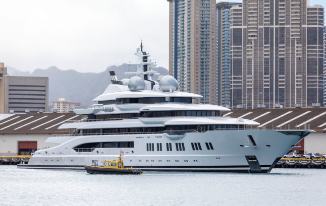 A harbor pilot boat cruises past the yacht Amadea of sanctioned Russian Oligarch Suleiman Kerimov, seized by the Fiji government at the request of the US, arrives at the Honolulu Harbor, Hawaii, June 16, 2022. A Fiji court on June 7 handed the Russian superyacht to US authorities and said it can be removed from the Pacific nation, ending a contested eight-week stay. The $300 million Amadea, linked by the United States to billionaire Russian politician Suleiman Kerimov, a target of sanctions, was impounded on arrival in Fiji in April at Washington's request. (Photo by Eugene TANNER / AFP) (Photo by EUGENE TANNER/AFP via Getty Images)