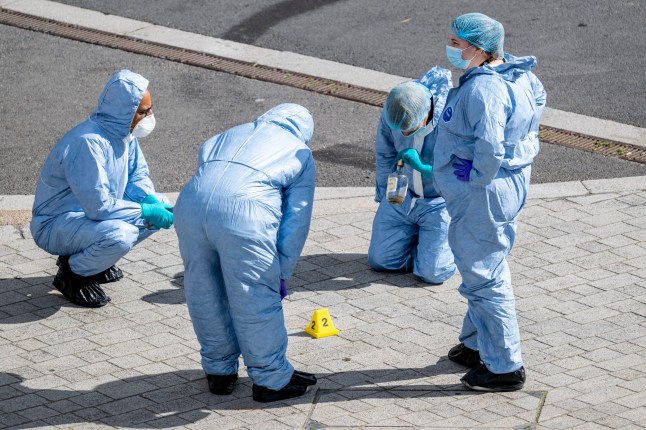 Forensics officers examining a bottle of alcohol next to an evidence marker at a crime scene near Wembley Stadium following a reported shooting in Atlantic Crescent after police and ambulance service were called at 5.30am. A patient has been taken to a major trauma centre and nearby roads, including South Way, are closed as enquiries continue. Photo credit: Stephen Chung/LNP