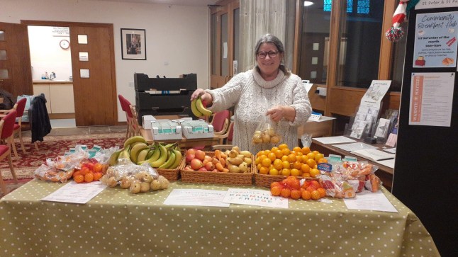 Liz Lockwood in front of a table of fruit at her community fridge