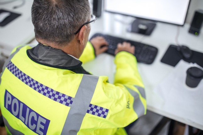 One senior traffic warden sitting at the office in front of the computer and writing a report