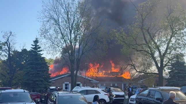 People gather at the site as smoke and fire rise, following an incident in which a man crashed his vehicle through the front doors of a Michigan church and opened fire with an assault rifle and set the church ablaze, in Grand Blanc, Michigan, U.S., September 28, 2025, in this screengrab obtained from social media video. Heem Vaniawala/via REUTERS THIS IMAGE HAS BEEN SUPPLIED BY A THIRD PARTY. MANDATORY CREDIT. NO RESALES. NO ARCHIVES. VERIFICATION - Reuters was able to verify the location by building characteristics and window panels matching file imagery as well as original file metadata from source which shows GPS coordinates. - Date of the video was verified by original file metadata from source