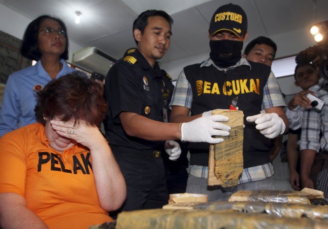 Indonesia custom officers observe drug evidence as British citizen Lindsay Sandiford, left, covers her face during a press conference in Kuta, Bali, Indonesia Monday, May 28, 2012. Indonesian custom said they arrested the British woman on May 19, 2012 for allegedly attempting to smuggle cocaine in her bag. (AP Photo/Firdia Lisnawati)