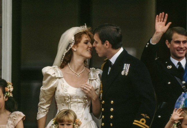 On the balcony of Buckingham Palace, Sarah, Duchess of York and Prince Andrew, Duke of York kiss each other after their wedding, London, England, July 23, 1986. Among those with them is best man (and brother of the groom) Prince Edward, Earl of Wessex (right). (Photo by Derek Hudson/Getty Images)