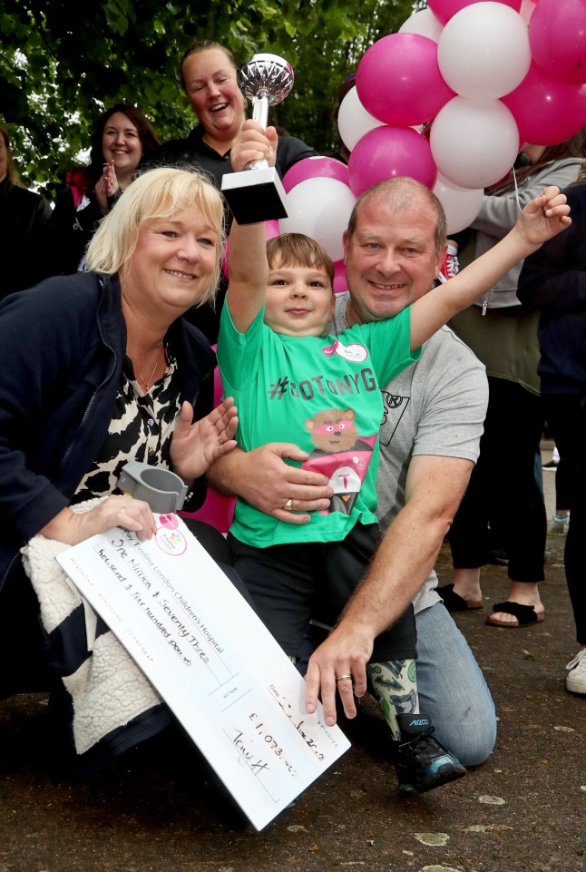 Tony Hudgell, who uses prosthetic legs, holds a trophy after taking the final steps in his fundraising walk in West Malling Kent, with mum, Paula and dad Mark. Five-year-old Tony has raised more than ?1,000,000 for the Evelina London Children's Hospital, who have cared for him since he was four-months-old, by walking every day in June, covering a distance of 10 kilometres.
