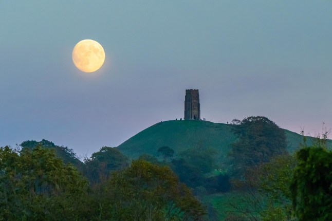 UK Weather. The almost full Harvest Moon moon rises up in to the almost clear evening sky above Glastonbury Tor at Glastonbury in Somerset at dusk. This months full moon on 7th October will be the first of a run of three supermoons in the final three months of 2025.