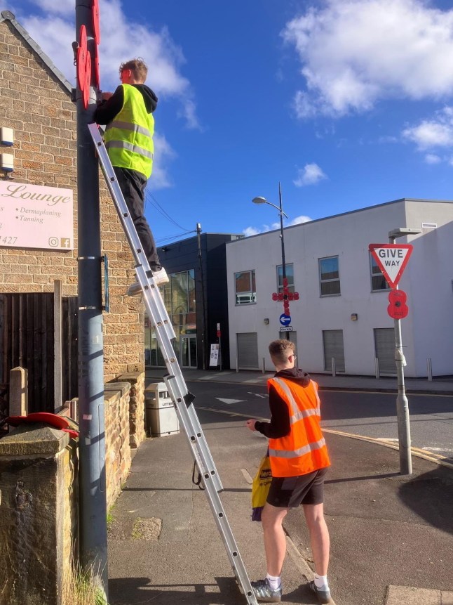 Volunteers putting poppies on a lamp post in the town of Hoyland, Barnsley, Yorkshire. A heartbroken community group have axed their remembrance day poppy displays after the council tightened their rules due to flags.The Hoyland Remembrance and Parade Group (HRPG) in Barnsley, South Yorks., have said new requirements issued by the Barnsley council mean they can no longer hang poppies on landposts.For the past three years the group have placed 350 wooden poppies - each bearing a fallen soldier's name - along the town?s remembrance parade route in preparation for Armistice Day.But under the Highways Act updated safety rules for lamppost decorations mean they can no longer install the the red remembrance flowers. Photo released 19/10/2025