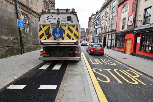 A bus stop in the middle of a lane of traffic