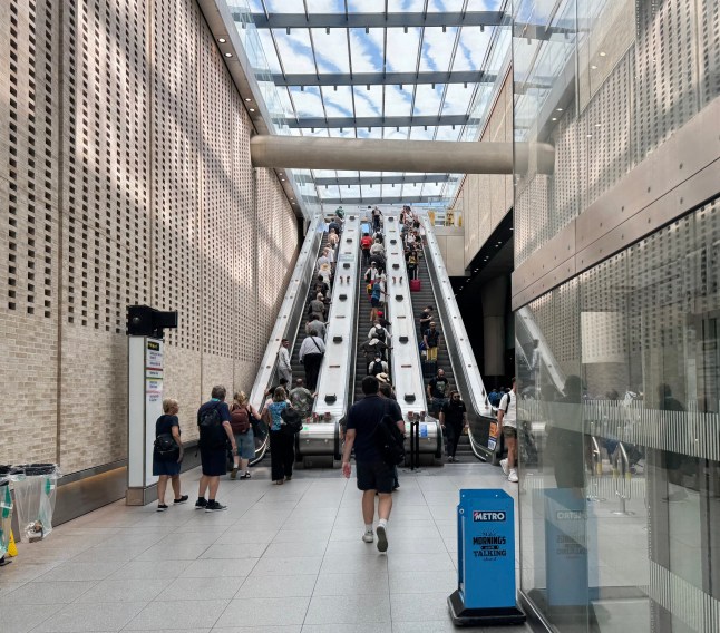 Large group of people on escalators at Paddington Station in London. Moving from the London Underground station to the main line overground station. June 2025