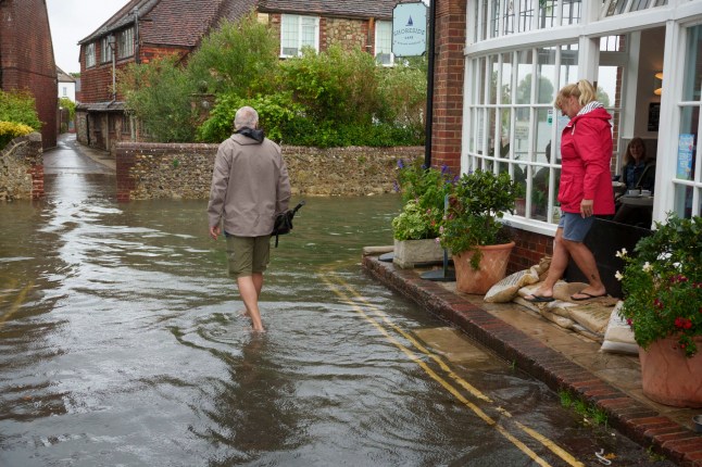 Carrying their footwear, locals negotiate flood waters during the highest high-tide of the year which has flooded lanes at Bosham, on 10th September 2025, in Bosham, England. Bosham's high-tide at 14.02 on the 10th September 2025, was a maximum of 5.04 metres. (Photo by Richard Baker / In Pictures via Getty Images)