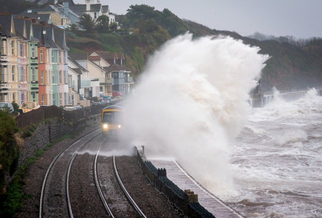 Waves batter the coastline at Dawlish, Devon and drown a train