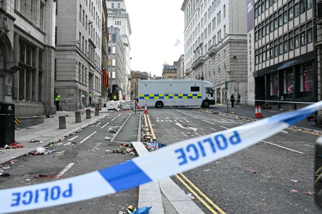 (FILES) Police officers stand at a cordon on in Water Street in Liverpool, north-west England on May 27, 2025, after a car ploughed in to crowds gathered to watch an open-top bus victory parade for Liverpool's Premier League trophy parade. The sentencing hearing for British man Paul Doyle who ploughed his car through crowds of fans celebrating Liverpool's Premier League victory in May, injuring over 100 people, is set to begin on December 15, 2025. (Photo by Paul ELLIS / AFP via Getty Images)