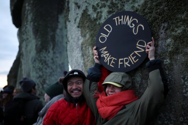 A person holds a sign during the winter solstice celebrations at Stonehenge stone circle near Amesbury, Britain, December 21, 2025. REUTERS/Isabel Infantes