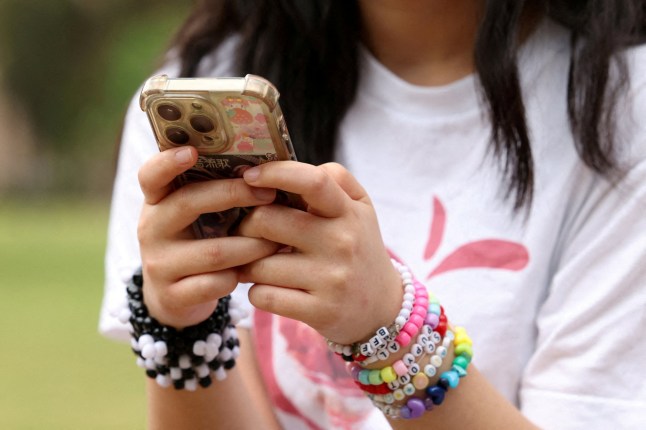 A girl poses holding her phone after an interview discussing Australia's social media ban for users under 16, which is scheduled to take effect on December 10, in Sydney, Australia, November 22, 2025. REUTERS/Hollie Adams