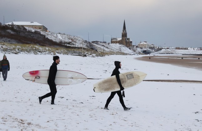 Dated: 05/01/2026 MONDAY MORNING FRESH SNOWFALL pictured surfers walking on the sand covered in snow after more snowfall on the coastal village of Tynemouth in North Tyneside , see copy by North News