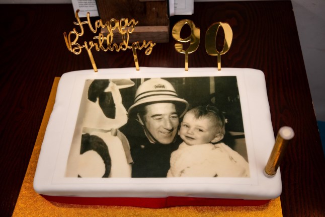 Brian's birthday cake featured an image of him after rescuing baby Carly 40 years ago. // A retired firefighter was left stunned on his 90th birthday when he was reunited with the baby girl whose life he saved 40 years ago. Brian Passmore, who spent more than 25 years with the Lancashire Fire Service, never forgot that fateful day in 1986 when he rescued baby Carly Holden from a burning home in Blackpool, Lancs. Now a mum-of-five, Carly had kept cuttings of the rescue for decades - but she and Brian had never met until his milestone birthday party. Brian, who now lives in a care home, thought he was heading out for a quiet lunch at a nearby pub with his daughter Julie Henderson to celebrate the big day. Photo released 05/01/2026