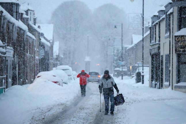 HUNTLY, UNITED KINGDOM - JANUARY 5: People walk in the roads during a snowfall on January 5, 2026 in Huntly Scotland, United Kingdom. The Met Office has given a weather warning of disruption to travel as many people return to work and school following the Christmas break. (Photo by Jeff J Mitchell/Getty Images)
